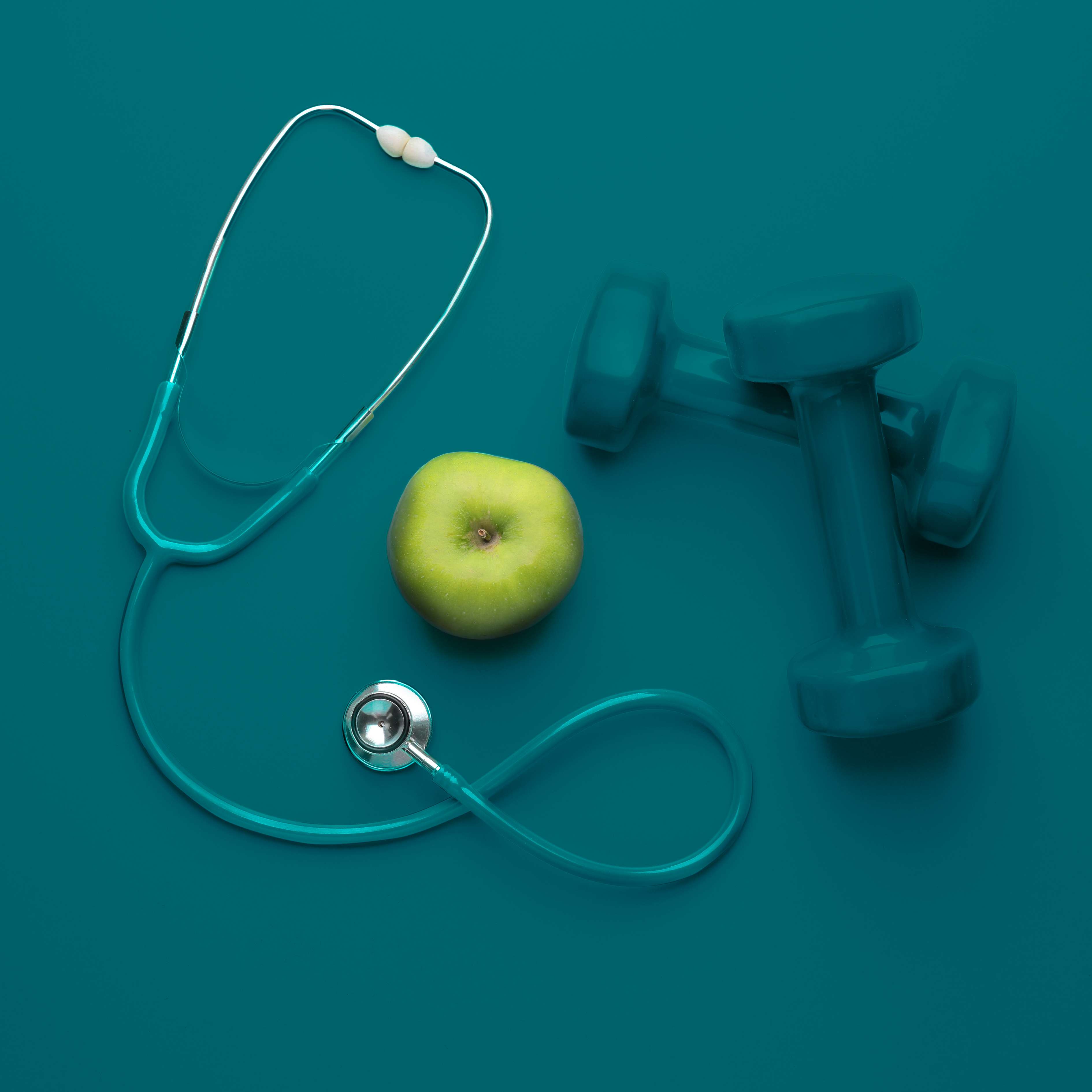 Stethoscope, apple, and dumbbells representing functional health and wellness.